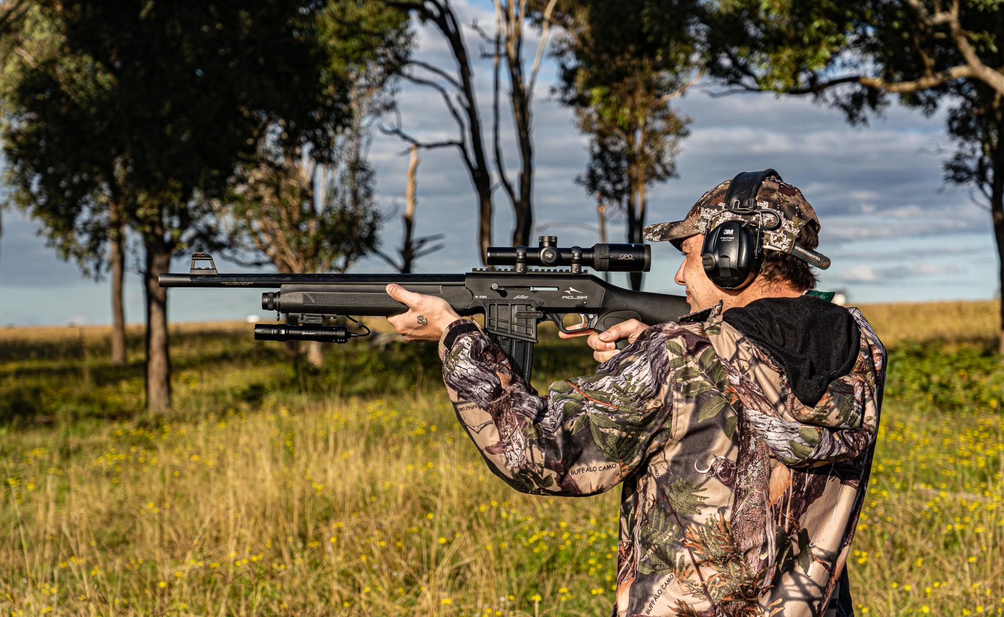 Man hunting out back with gun in camo by a lake image